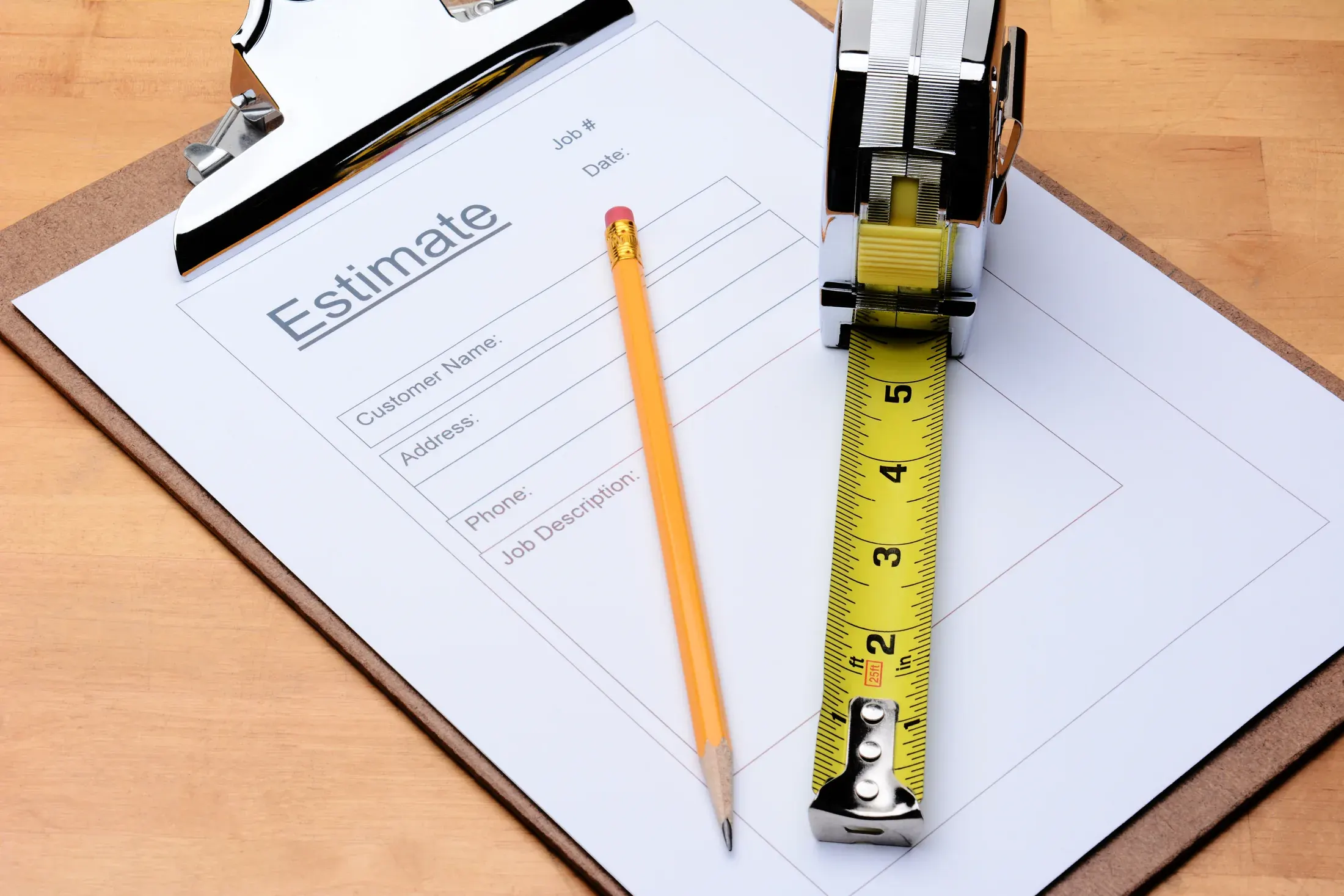 A written flooring estimate sheet, pencil, and tape measure laid out on a table