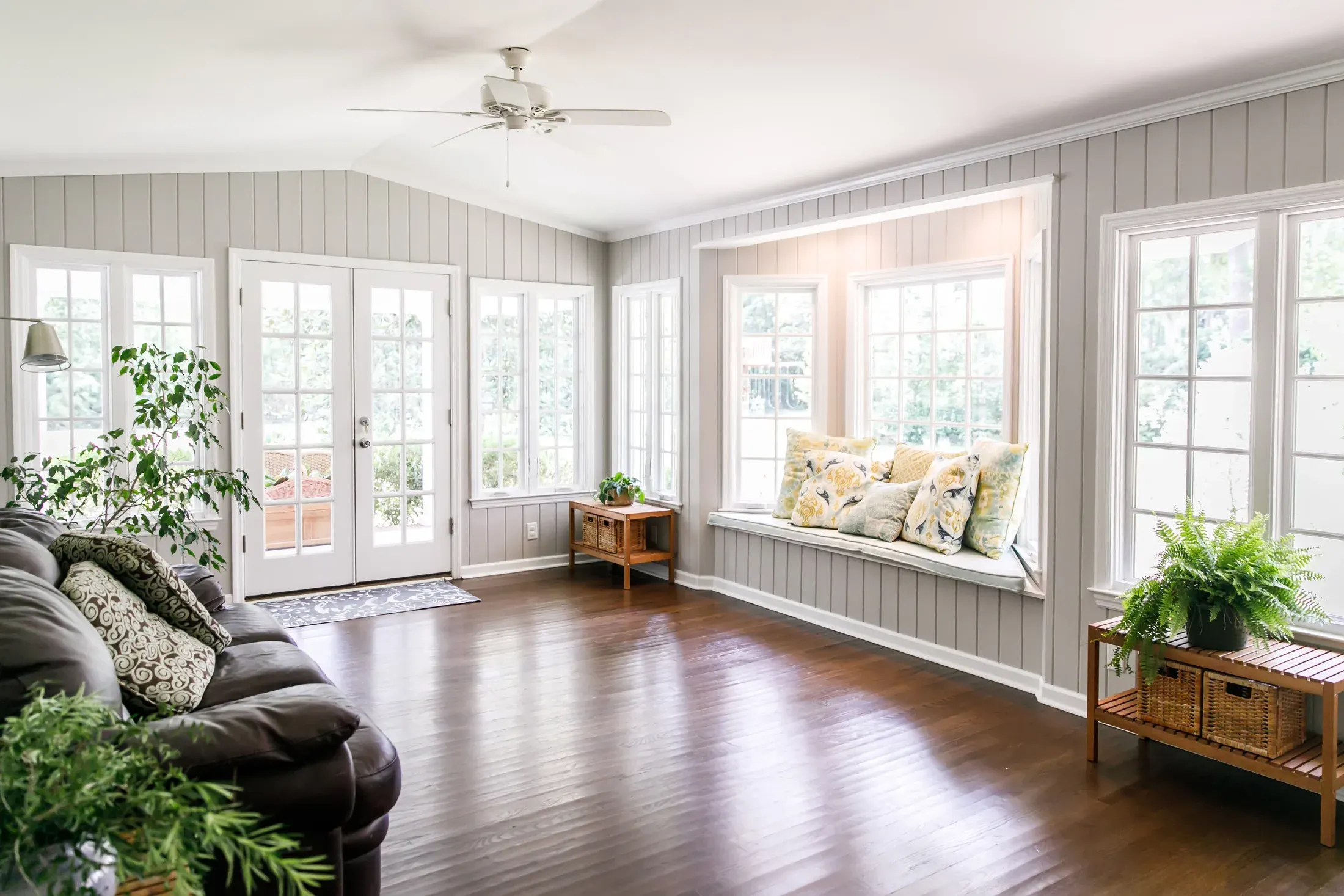 Bright living room with newly installed warm-toned hardwood flooring and a window seat