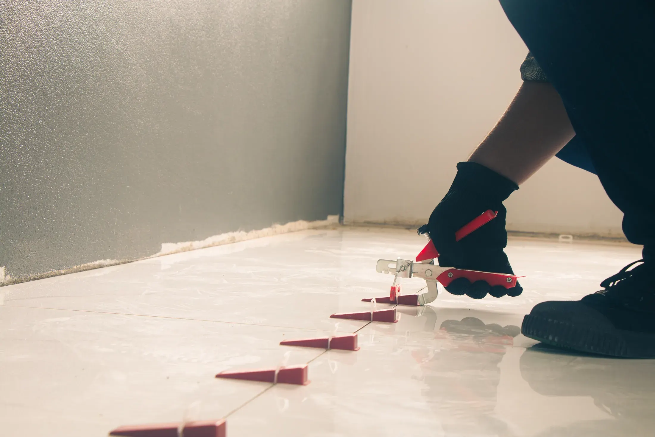 Plastic tile spacers being placed between large floor tiles during installation